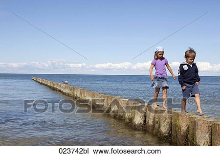 sister and brother walking on poles at seaside View Large Photo Image Stock Image - sister and brother walking on poles at seaside. Fotosearch