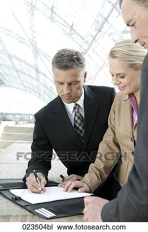 Stock Image - three business people signing document. Fotosearch