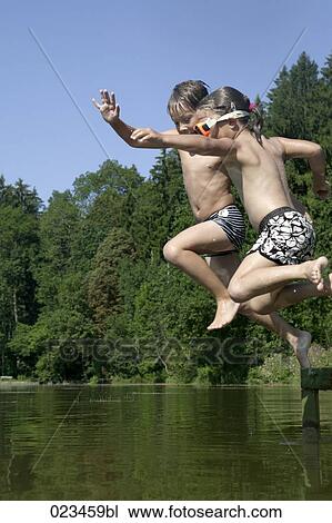young boy and girl jumping into lake View Large Photo Image Stock Image - young boy and girl jumping into lake . Fotosearch