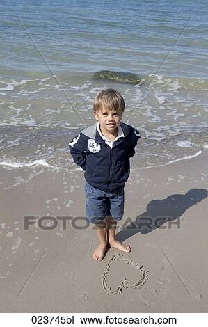 young boy standing on beach in front of heart drawn into sand View Large Photo Image Stock Image - young boy standing on beach in front of heart drawn into sand. Fotosearch