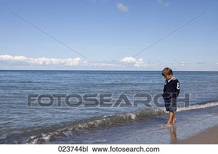 young boy standing on beach View Large Photo Image Stock Image - young boy standing on beach. Fotosearch