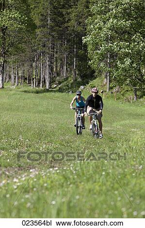 young couple cycling through nature View Large Photo Image Stock Image - young couple cycling through nature. Fotosearch