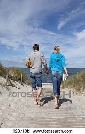 young couple walking towards the beach hand in hand View Large Photo Image Stock Image - young couple walking towards the beach hand in hand. Fotosearch