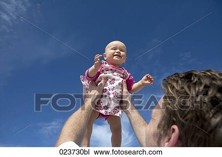 young father holding baby up in the air View Large Photo Image Stock Image - young father holding baby up in the air. Fotosearch