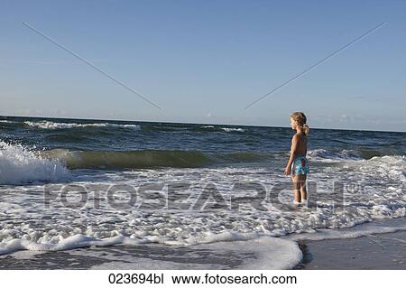 young girl standing on beach in surf View Large Photo Image Stock Image - young girl standing on beach in surf. Fotosearch