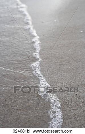 Stock Image - close-up of surf at sandy beach. Fotosearch