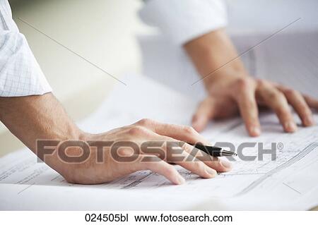 Stock Image - detail of businessman working on blueprint. Fotosearch