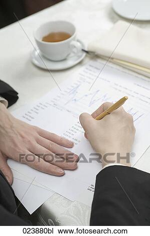 Stock Image - detail of businesswoman writing document during business lunch. Fotosearch
