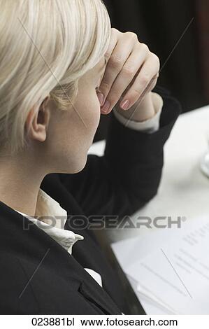 Stock Image - exhausted businesswoman sitting at table. Fotosearch