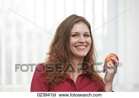 Stock Image - headshot of young businesswoman holding apple. Fotosearch