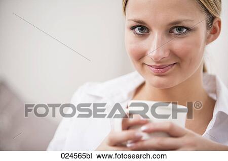 Stock Image - headshot of young woman holding coffee cup. Fotosearch
