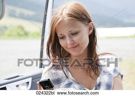 Stock Image - headshot of young woman resding test message on mobile phone. Fotosearch