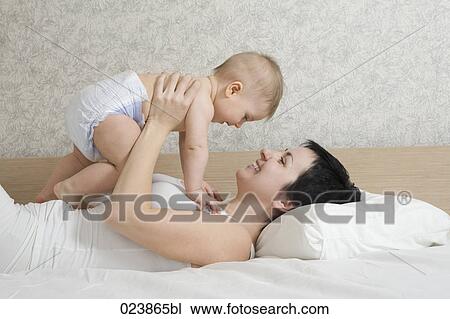 Stock Image - mother holding baby boy up in the air. Fotosearch