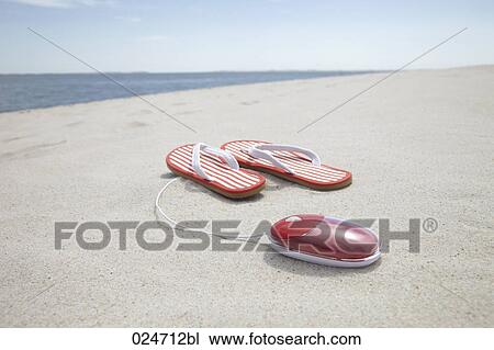 Stock Image - pair of flip flops and computer mouse on sandy beach. Fotosearch