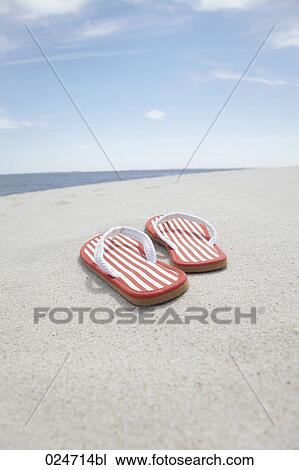 Stock Image - pair of flip flos on sandy beach. Fotosearch