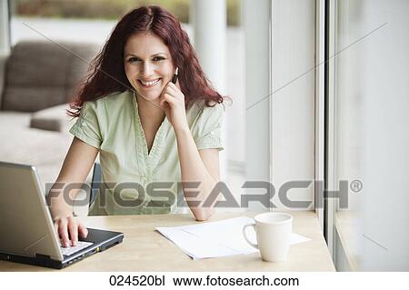 Stock Image - portrait of red haired businesswoman working with laptop computer. Fotosearch