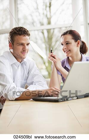 Stock Image - portrait of two business people at table with laptop computer. Fotosearch
