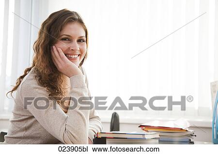 portrait of young bsinesswoman sitting at desk View Large Photo Image Stock Image - portrait of young bsinesswoman sitting at desk. Fotosearch