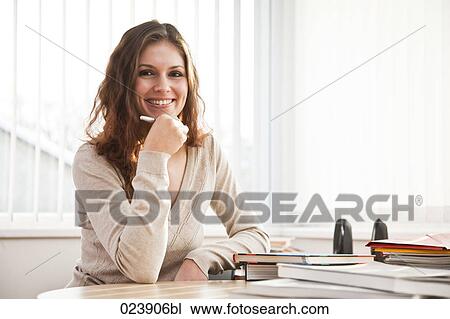 Stock Image - portrait of young bsinesswoman sitting at desk. Fotosearch