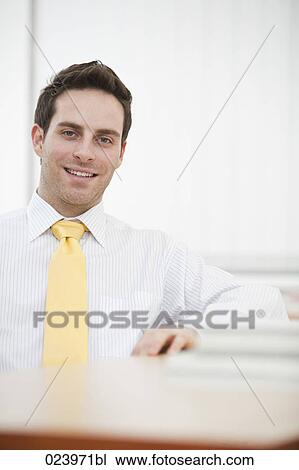 Stock Image - portrait of young businessman at desk. Fotosearch
