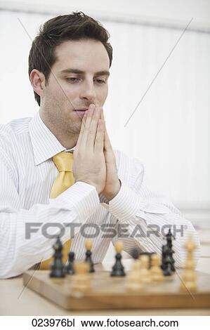 Stock Image - portrait of young businessman playing chess. Fotosearch
