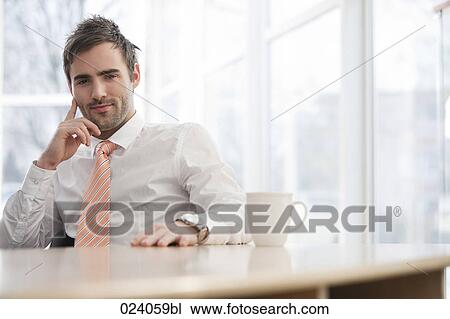 portrait of young businessman sitting at table View Large Photo Image Stock Image - portrait of young businessman sitting at table. Fotosearch