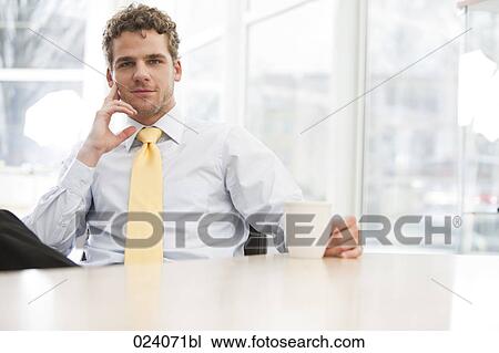 portrait of young businessman sitting at desk with cup View Large Photo Image Stock Image - portrait of young businessman sitting at desk with cup. Fotosearch