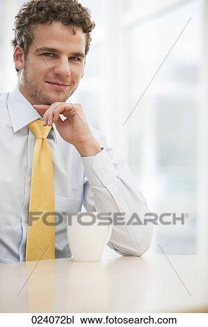 portrait of young businessman sitting at desk with cup View Large Photo Image Stock Image - portrait of young businessman sitting at desk with cup. Fotosearch