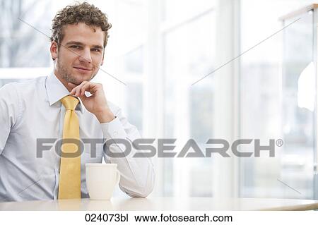portrait of young businessman sitting at desk with cup View Large Photo Image Stock Image - portrait of young businessman sitting at desk with cup. Fotosearch