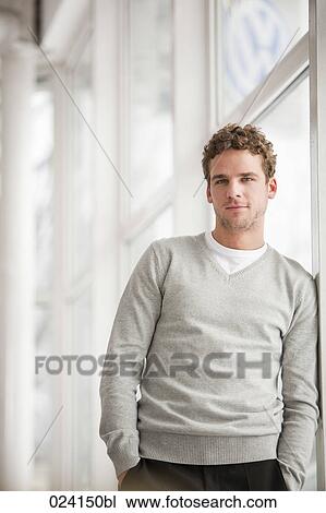 portrait of young businessman standing by a window View Large Photo Image Stock Image - portrait of young businessman standing by a window. Fotosearch