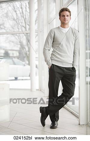 Stock Image - portrait of young businessman standing by a window. Fotosearch