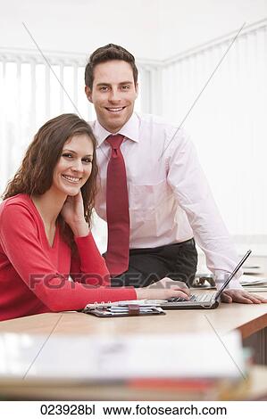 portrait of young businesswoman and male colleague sitting at desk View Large Photo Image Stock Image - portrait of young businesswoman and male colleague sitting at desk. Fotosearch