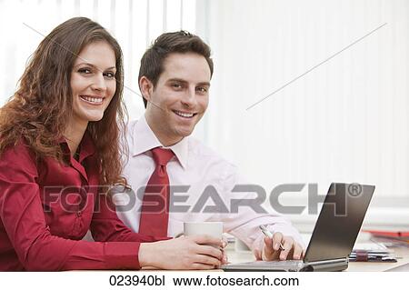 portrait of young businesswoman and male colleague sitting at desk View Large Photo Image Stock Image - portrait of young businesswoman and male colleague sitting at desk. Fotosearch