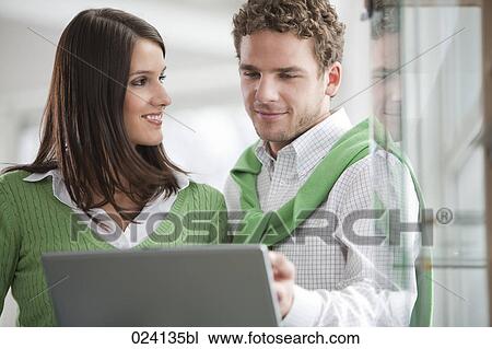 Stock Image - portrait of young businesswoman and male colleague looking at computer. Fotosearch