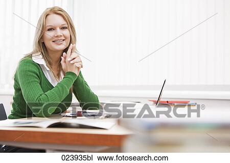 Stock Image - portrait of young businesswoman at desk. Fotosearch