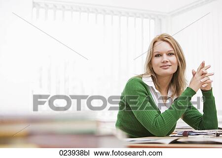 Stock Image - portrait of young businesswoman at desk. Fotosearch