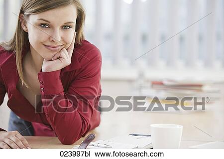 Stock Image - portrait of young businesswoman at desk. Fotosearch
