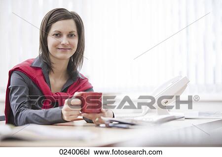 Stock Image - portrait of young businesswoman at desk. Fotosearch