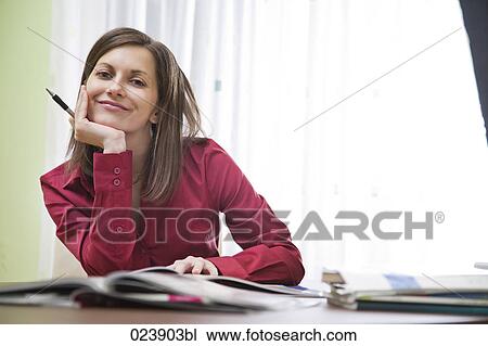 Stock Image - portrait of young businesswoman sitting at desk. Fotosearch