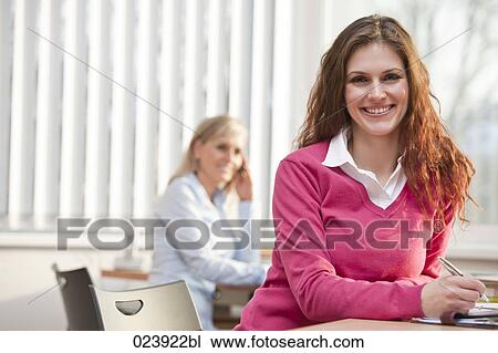 Stock Image - portrait of young businesswoman sitting at office desk. Fotosearch