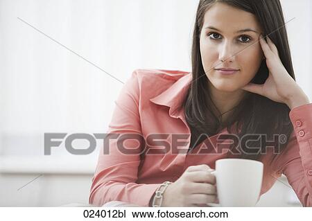 portrait of young businesswoman sitting at desk with cup View Large Photo Image Stock Image - portrait of young businesswoman sitting at desk with cup. Fotosearch