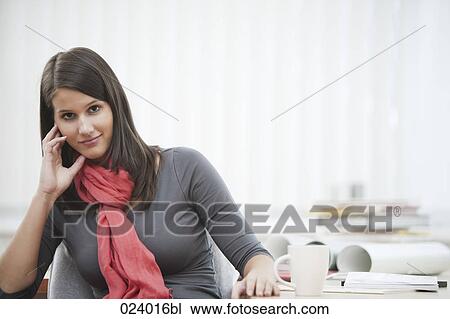 Stock Image - portrait of young businesswoman sitting at desk with cup. Fotosearch