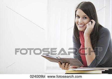 Stock Image - portrait of young businesswoman with diary and mobile phone. Fotosearch