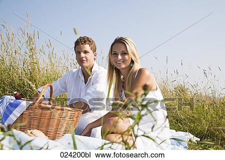Stock Image - portrait of young couple having picnic in meadow. Fotosearch