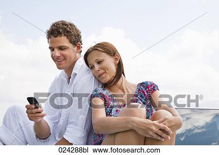 Stock Image - portrait of young couple man writing text message on mobile phone. Fotosearch
