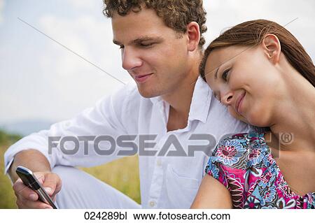Stock Image - portrait of young couple man writing text message on mobile phone. Fotosearch