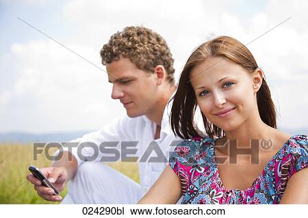 Stock Image - portrait of young couple man writing text message on mobile phone. Fotosearch