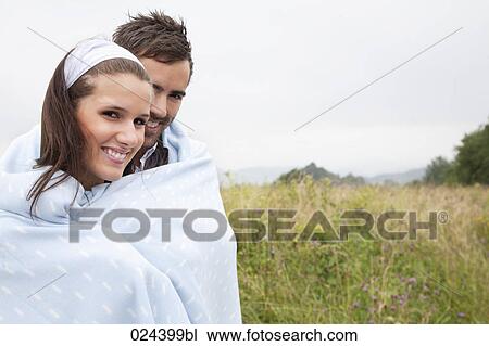 Stock Image - portrait of young couple outdoors wrapped in a blanket. Fotosearch