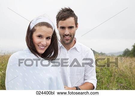 Stock Image - portrait of young couple outdoors woman wrapped in a blanket. Fotosearch
