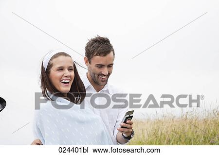 Stock Image - portrait of young couple outdoors woman wrapped in a blanket. Fotosearch